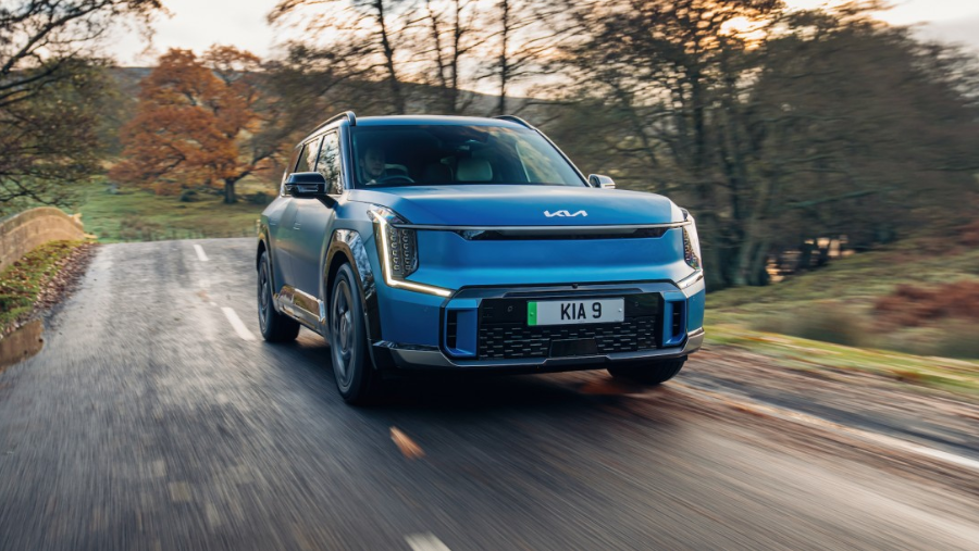 blue electric car driving on a wooded road